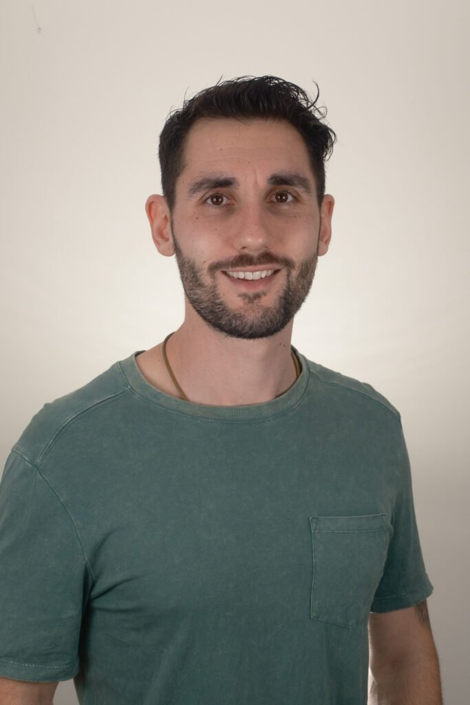 Simon in a relaxed green t-shirt, with a welcoming and warm smile.
