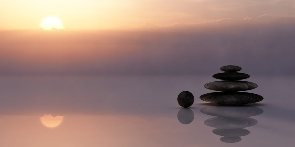 Stacked rocks on sand at sunset symbolizing balance, tranquility, and emotional presence in Gestalt therapy