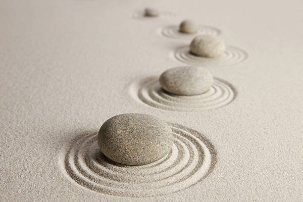 Arc of rippled stones on sand symbolizing balance, calmness, and humanistic therapy