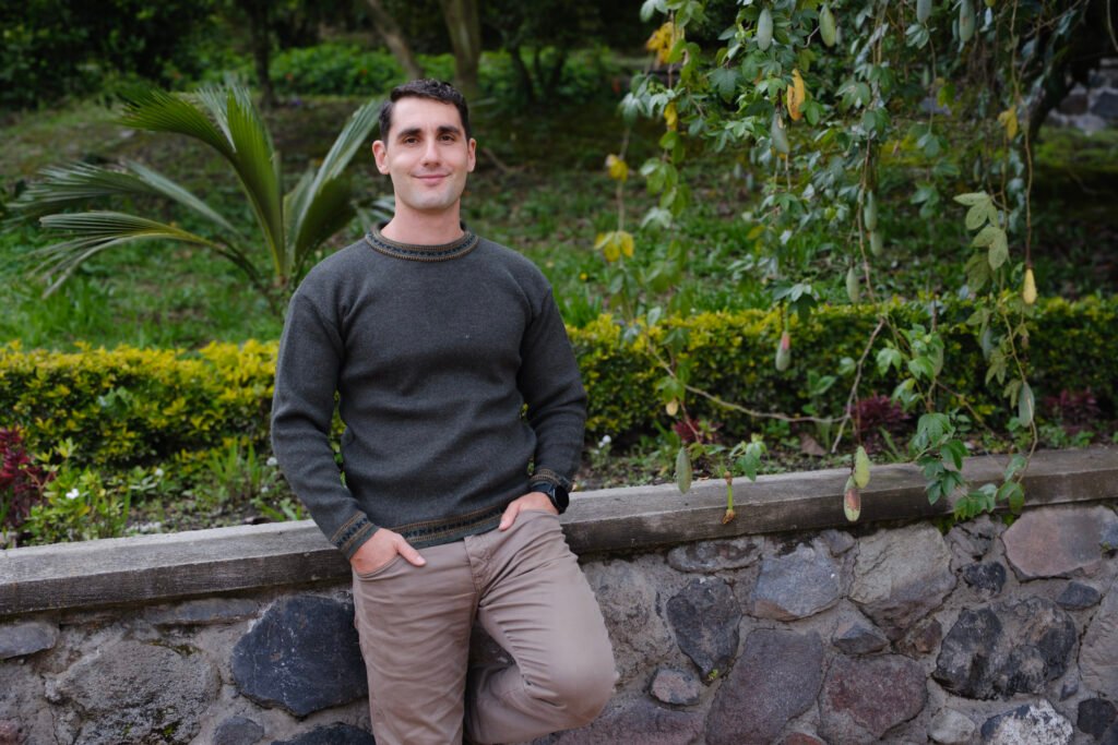 Simon Erlich, therapist in Ontario, leaning gently against a rock wall beside a vine, conveying care and compassion