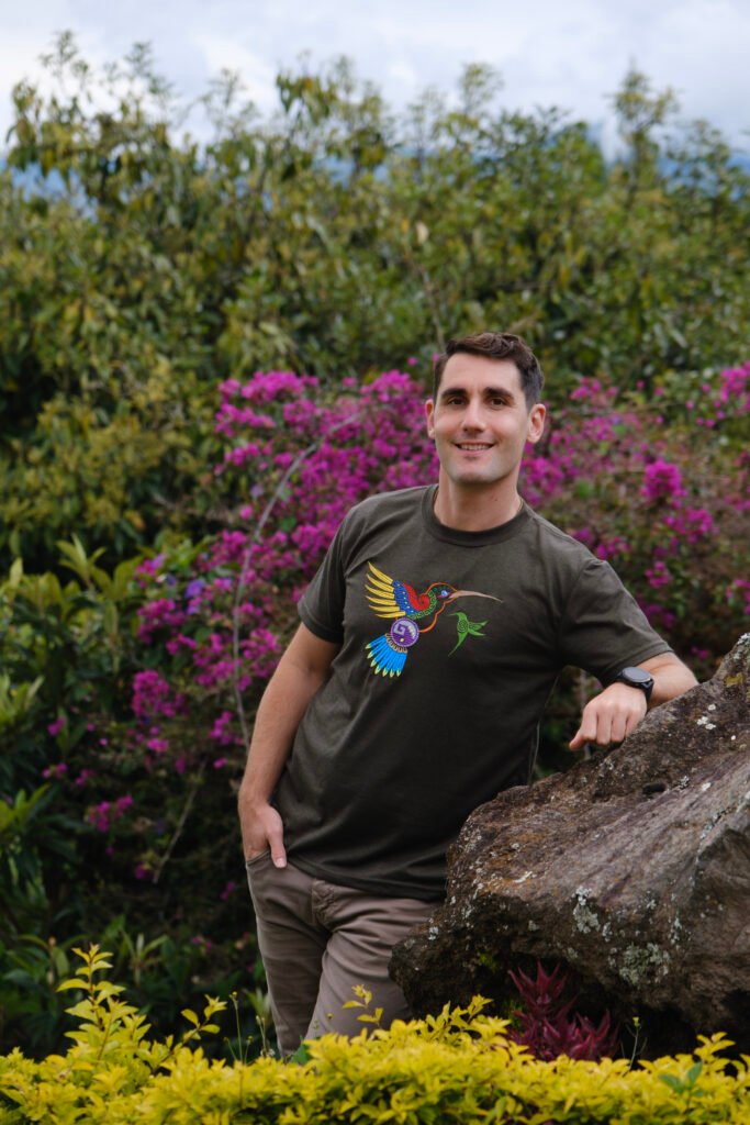 Simon Erlich, Ontario-based therapist, smiling warmly in front of purple flowers, reflecting kindness and ease